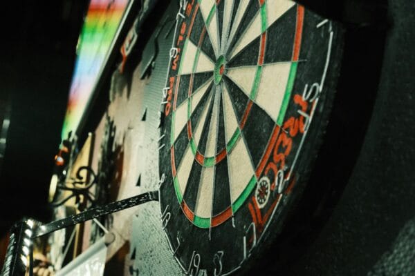 Dartspieler zieht seine Dartpfeile aus einem beleuchteten Steeldartboard