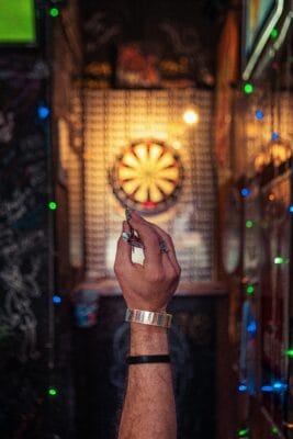 Dartspieler beim Wurf auf ein beleuchtetes Steeldartboard