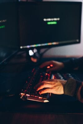 Person bedient Tastatur und Maus an einem Arbeitsplatz mit mehreren Monitoren