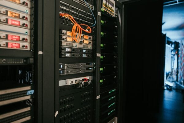 Serverrack mit Netzwerkgeräten, Servern und orangefarbenen Netzwerkkabeln in einem Rechenzentrum