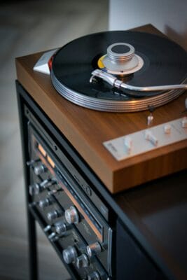 Plattenspieler mit Holzgehäuse, Schallplatte und silbernem Plattengewicht über weiteren HiFi-Komponenten.