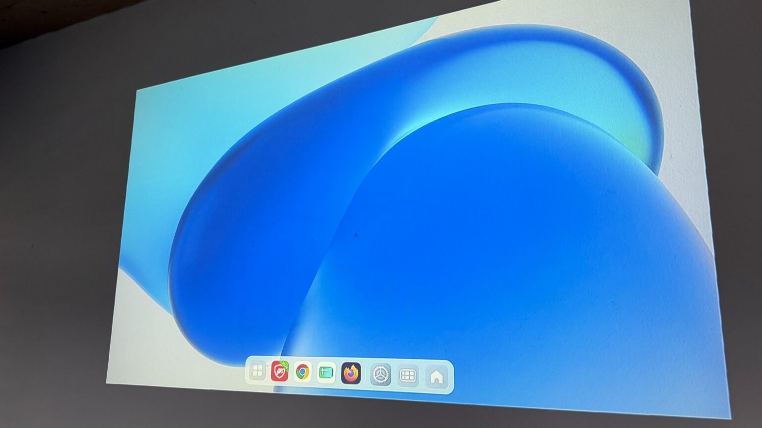 Kabellos übertragene Xiaomi-Tablet-Oberfläche mit blauem Hintergrund und App-Leiste auf einer Wand.